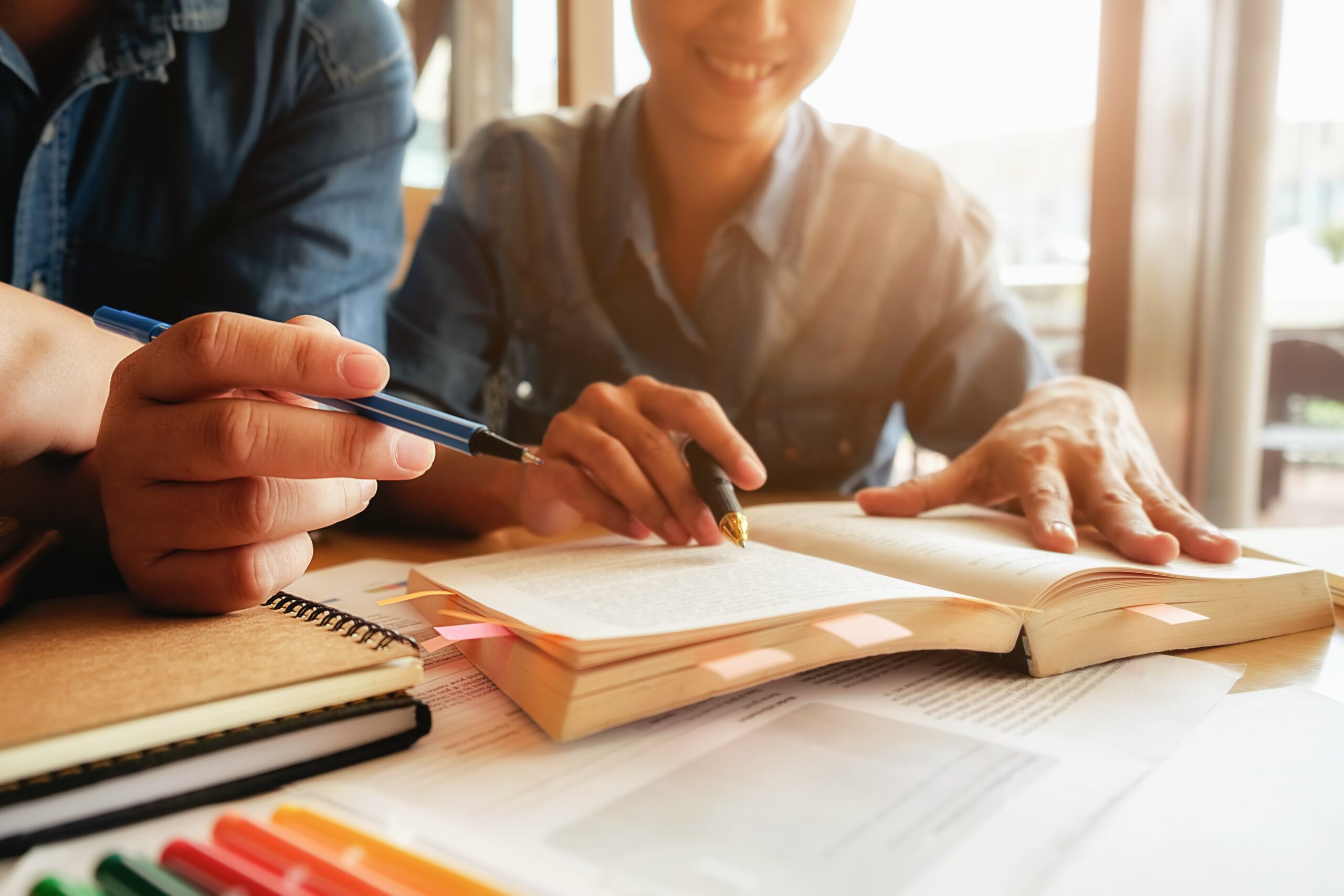 education-concept-student-studying-and-brainstorming-campus-concept-close-up-of-students-discussing-their-subject-on-books-or-textbooks-selective-focus-min